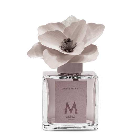 Diffusore ambiente Muha’ Ambra Antica con fiore in legno, profumo legnoso e floreale in vetro con etichetta ecopelle, design elegante made in Italy.